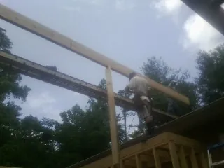 Carpenter setting a ridge beam over a new addition frame — Ice Dam Removal by Roofing Brothers in Mc Graw