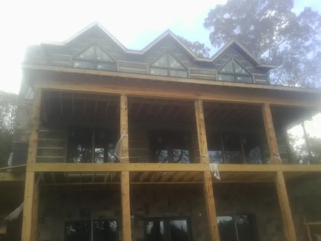 Dormers and porch framing on a large log home under construction — Roof Coating work by our crew in Mc Graw